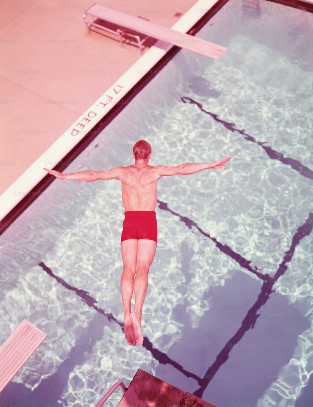 UNITED STATES - CIRCA 1950s:  Man diving into swimming pool, overhead view.