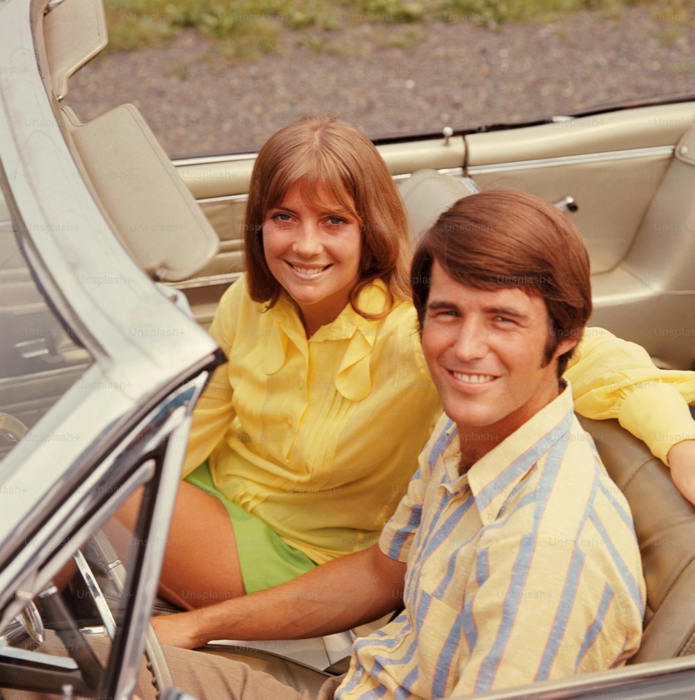 UNITED STATES - CIRCA 1960s:  Young couple in convertible car, portrait.