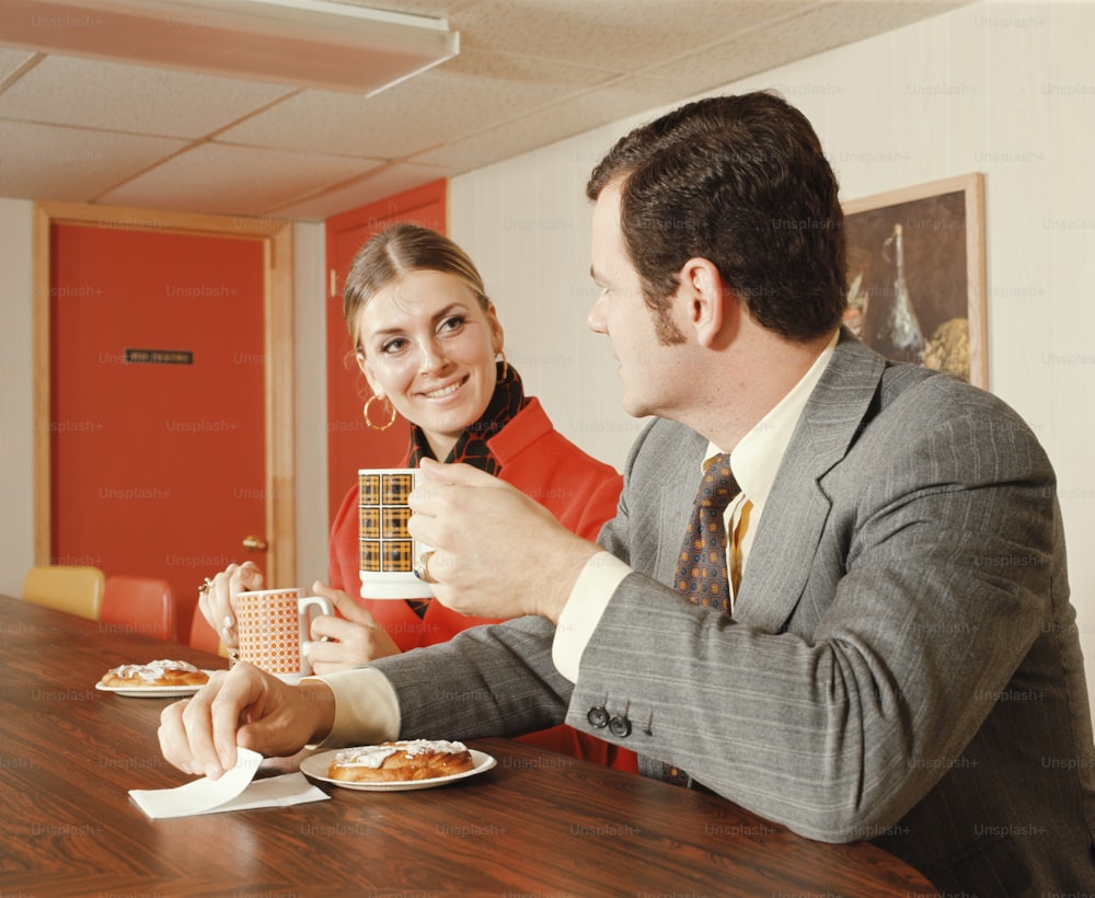 UNITED STATES - CIRCA 1970s:  Couple in coffee shop having breakfast Danish pastries and coffee.