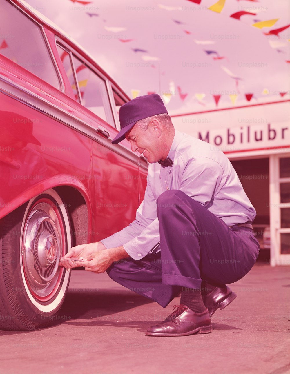 アメリカ合衆国 - 1960年代頃:車のタイヤの空気圧をチェックするガソリンスタンドの店員。