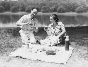 UNITED STATES - CIRCA 1930s:  Couple enjoying summer picnic.