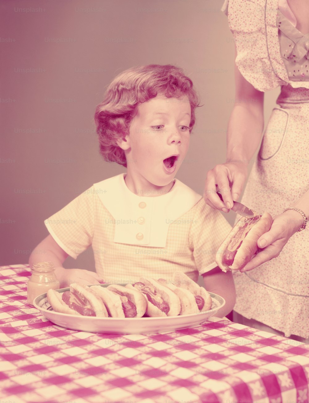 UNITED STATES - CIRCA 1950s:  Mother and daughter with hotdogs.