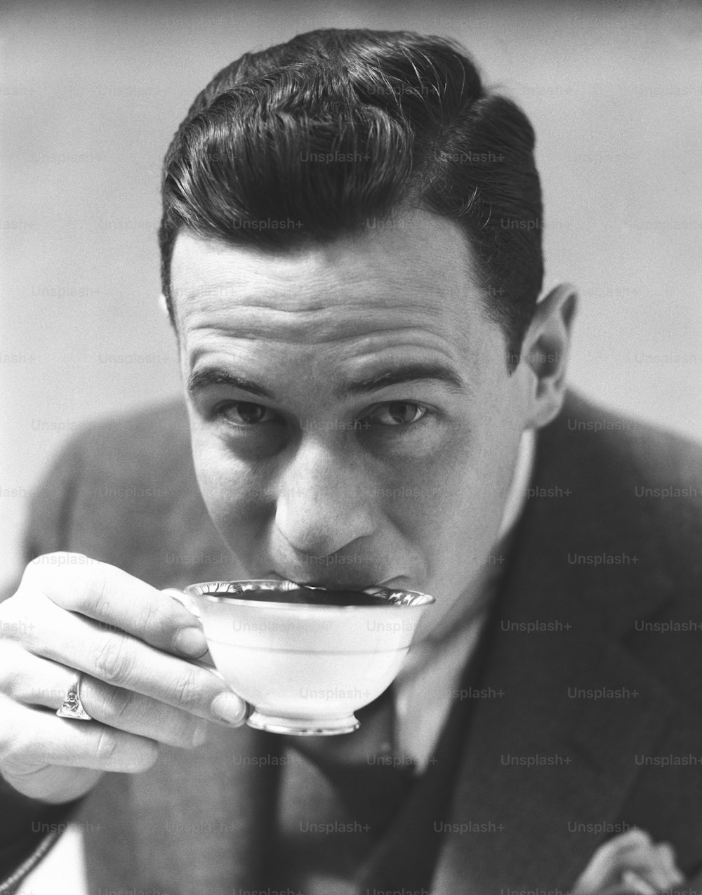 미국 - 1930년대경: 차이나 컵에서 차를 마시고 눈썹을 치켜올리는 남자.