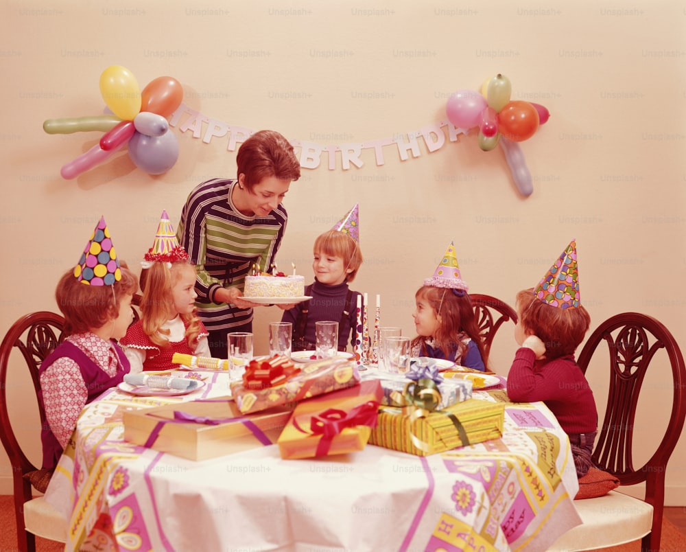 UNITED STATES - CIRCA 1970s:  Five children at birthday party, mother serving birthday cake.