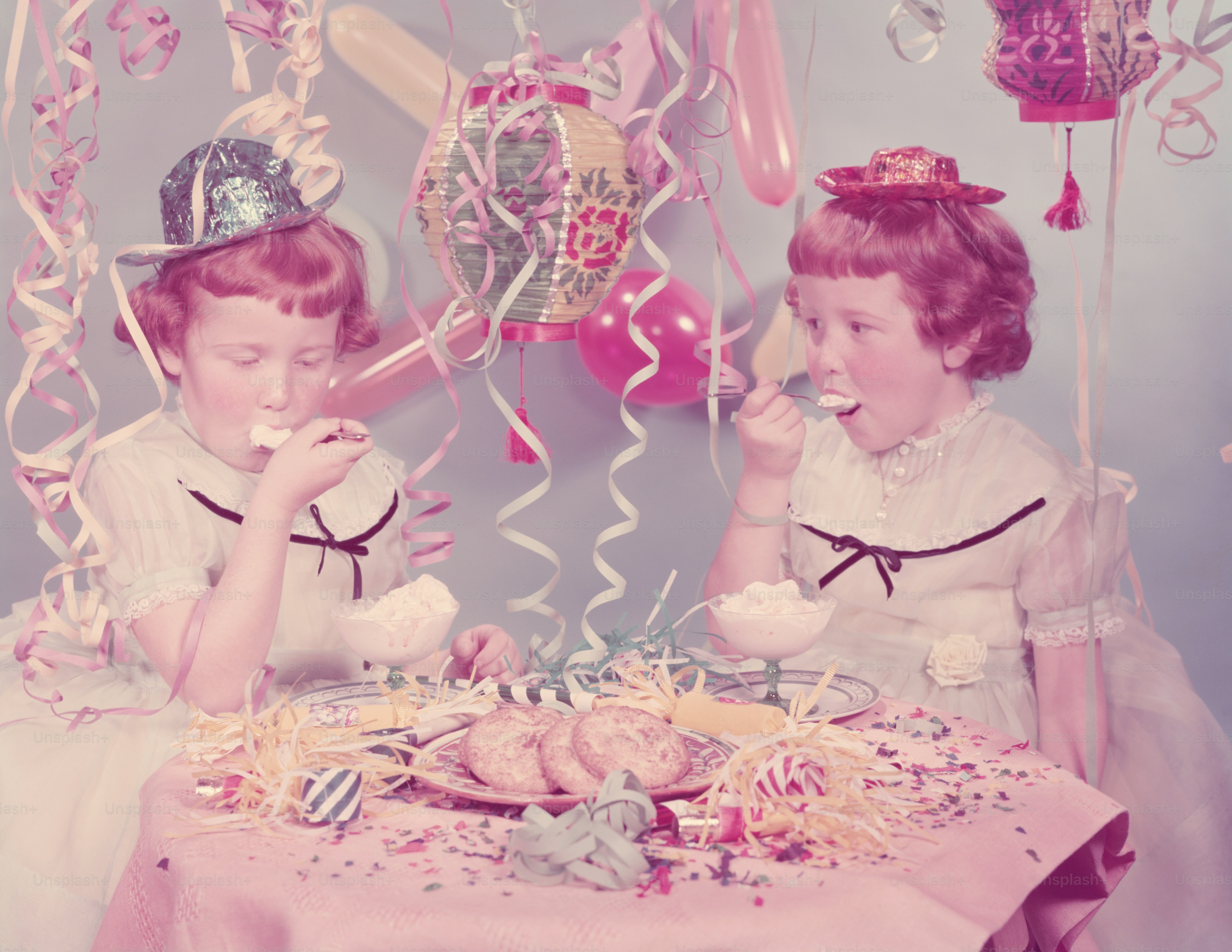 VEREINIGTE STAATEN - CIRCA 1950er Jahre: Zwillingsrothaarige, sommersprossige Mädchen, die auf der Geburtstagsfeier Eis essen