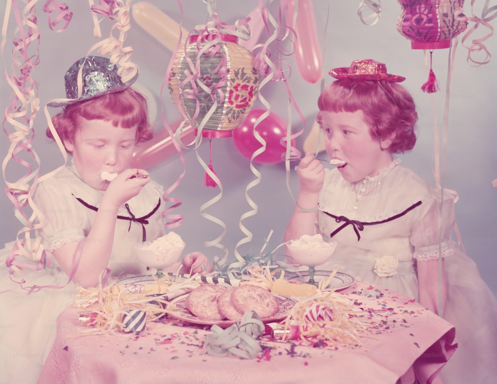 UNITED STATES - CIRCA 1950s:  Twin red haired, freckle faced girls eating ice cream at birthday party.