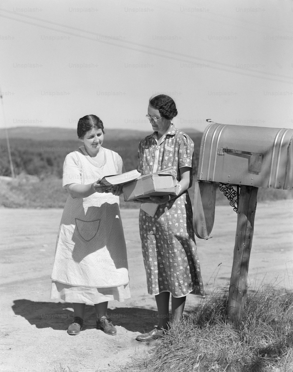 미국 - 1940년대경: 두 명의 여성이 국가 우편함에서 우편물을 수집합니다.