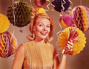 UNITED STATES - CIRCA 1960s:  Blonde woman smiling surrounded by confetti, balloons and party decorations.