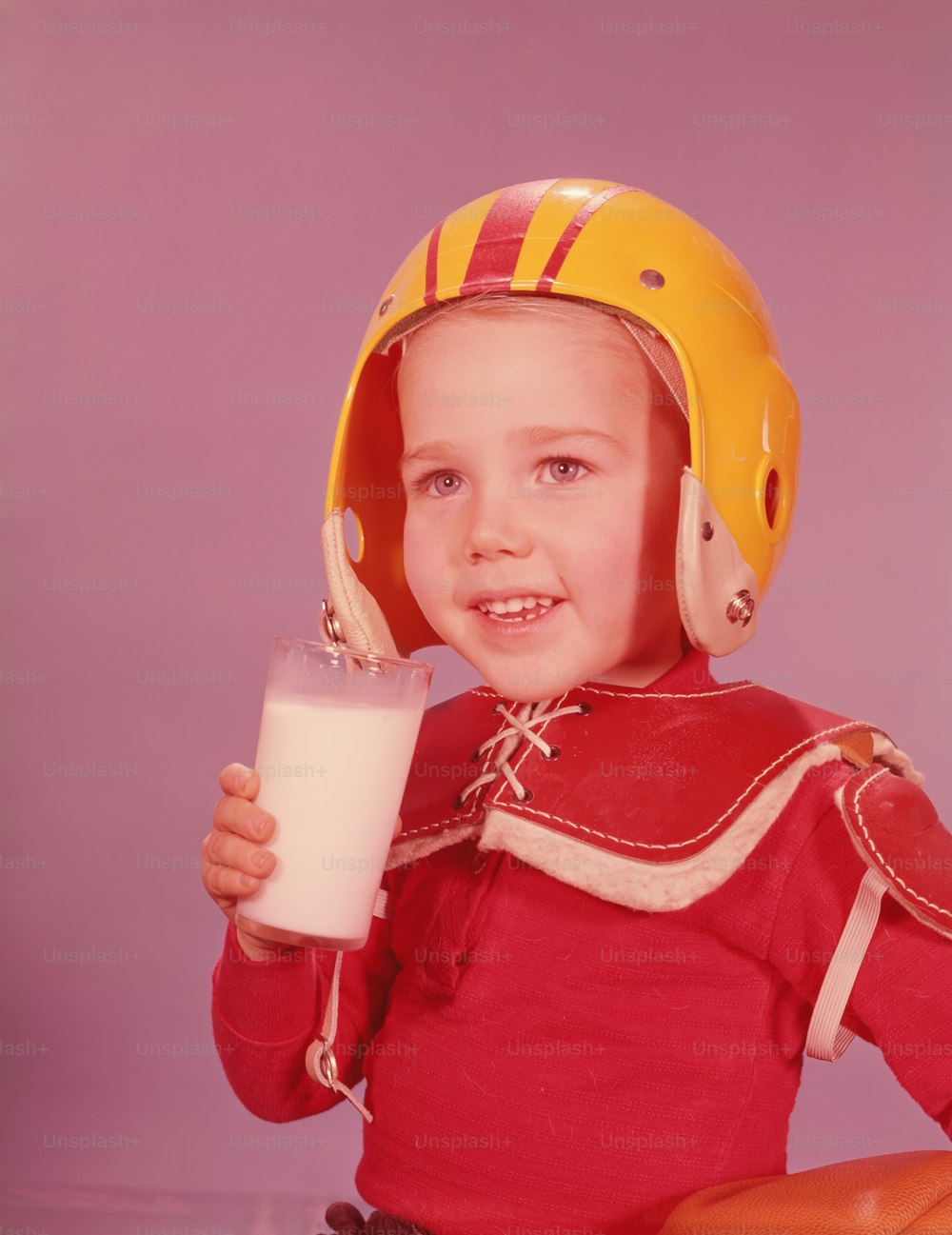 UNITED STATES - CIRCA 1960s:  Boy wearing American football kit, holding glass of milk.
