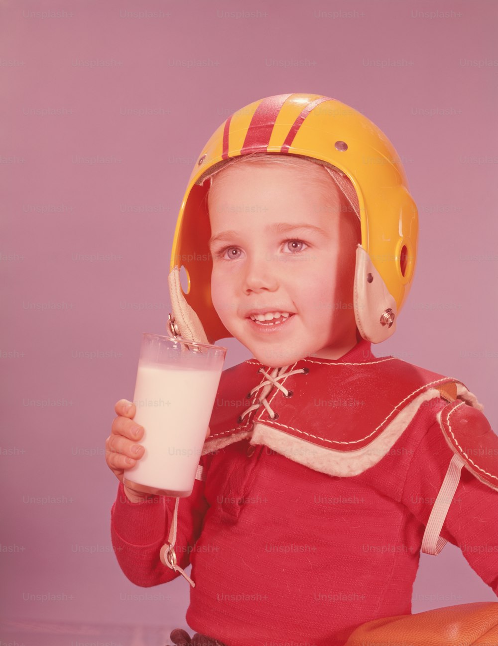 UNITED STATES - CIRCA 1960s:  Boy wearing American football kit, holding glass of milk.