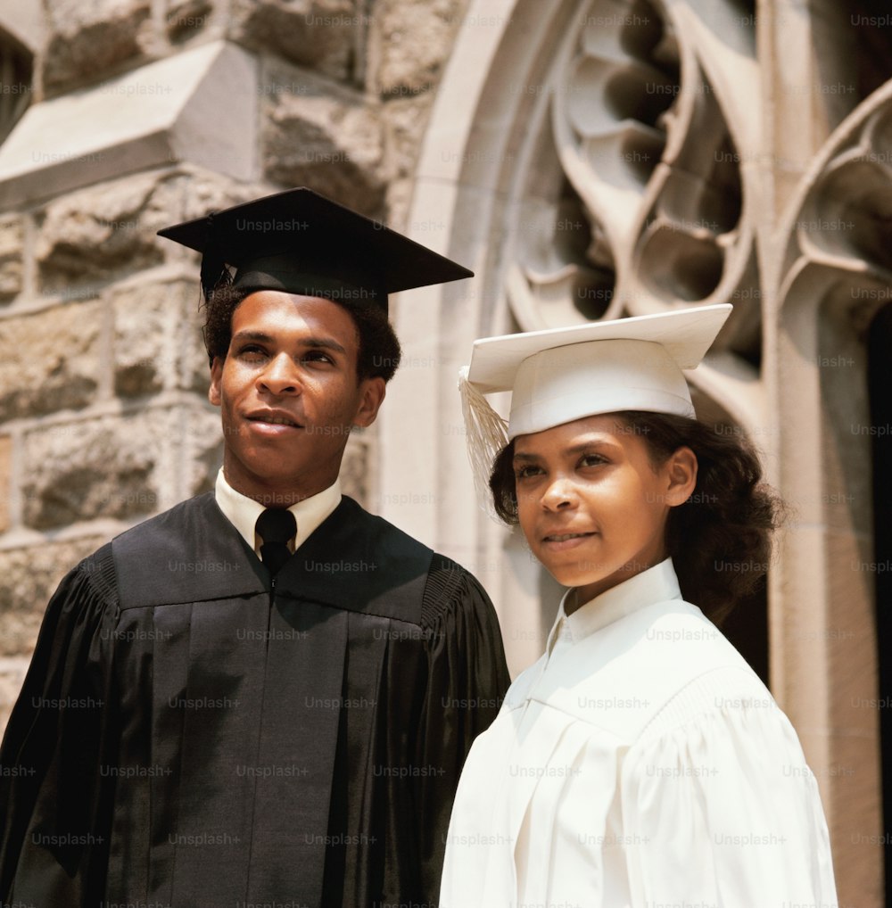 VEREINIGTE STAATEN - CIRCA 1970er Jahre: Teenager-Studentenpaar trägt Roben und Mörserbretter bei der Abschlussfeier.