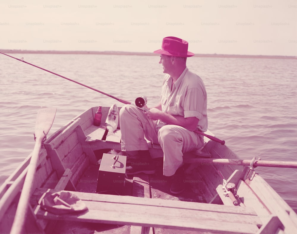미국 - 1950년대경: 노 젓는 배에 앉아 낚시를 하는 남자.