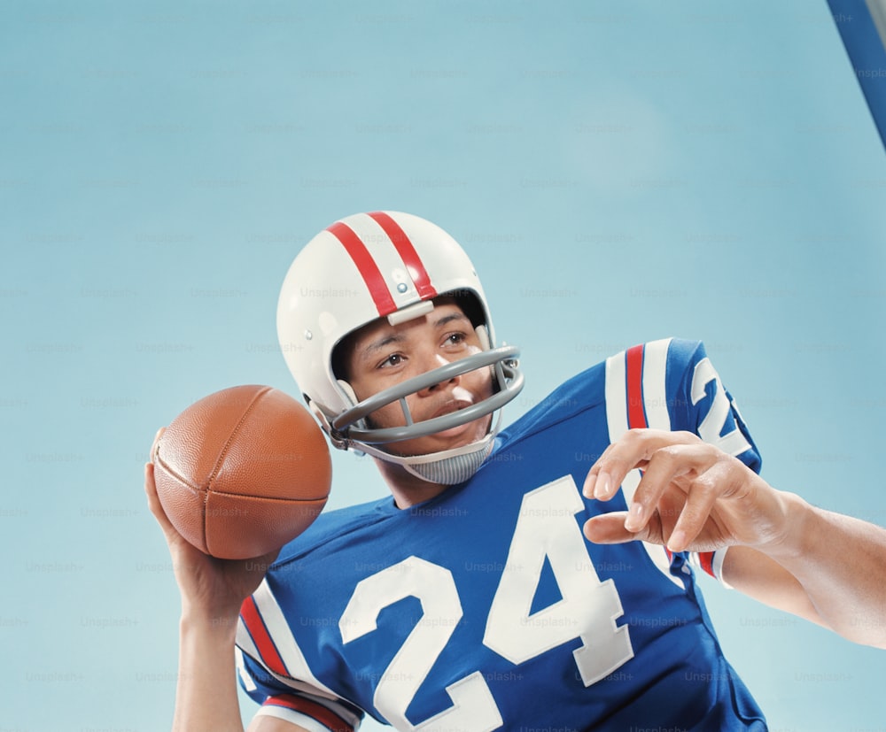 VEREINIGTE STAATEN - CA. 1970er Jahre: American-Football-Spieler hält den Ball hoch.
