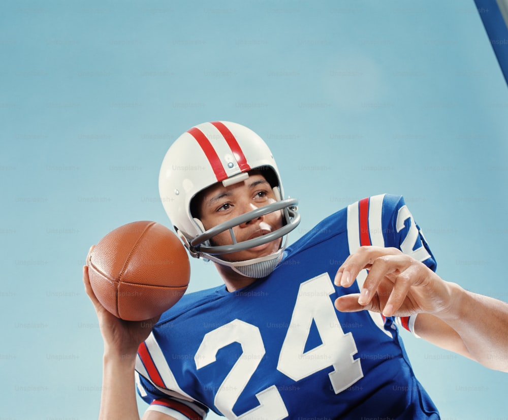 UNITED STATES - CIRCA 1970s:  American football player holding up ball.