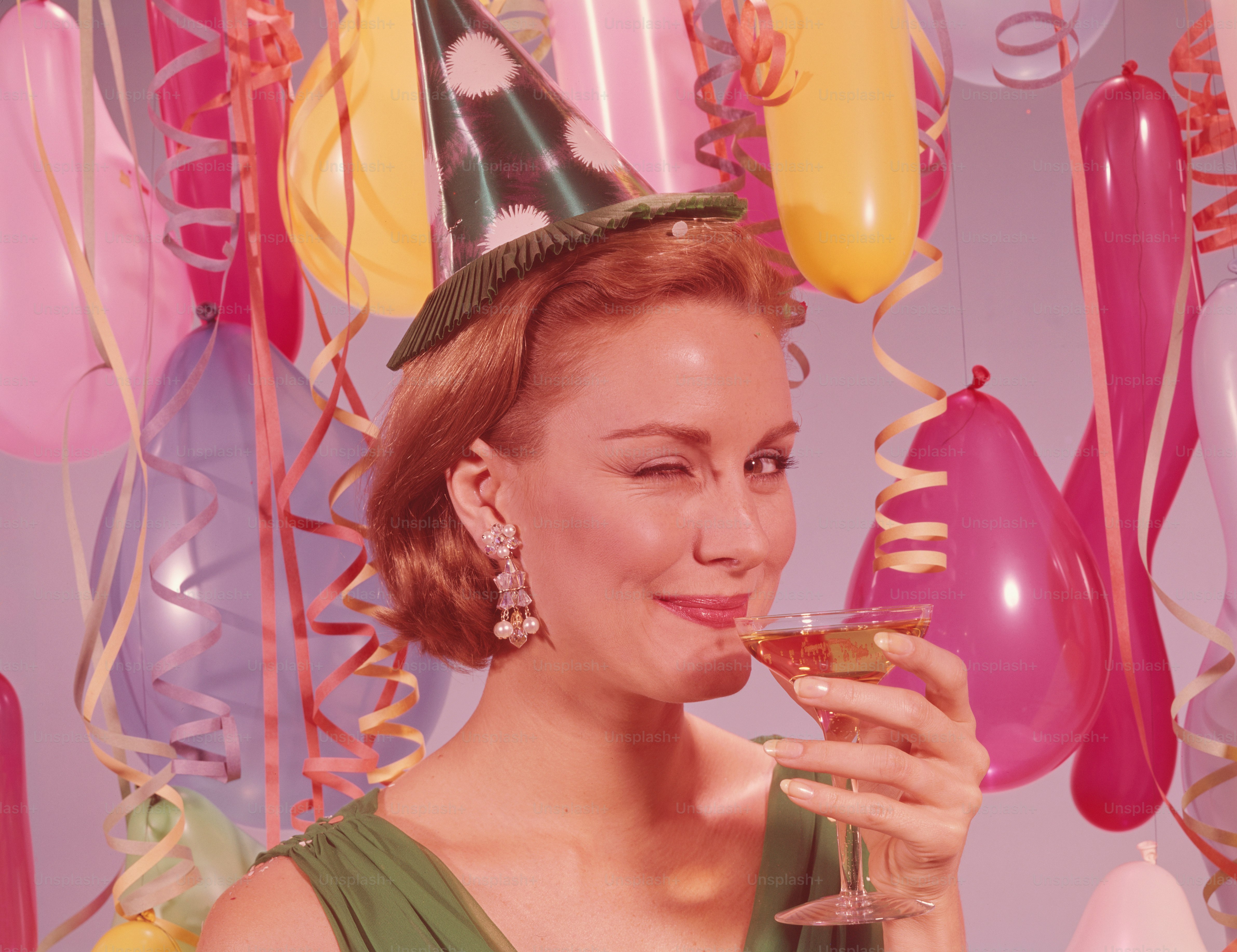 VEREINIGTE STAATEN - CIRCA 1960er Jahre: Frau auf der Party, mit Partyhut und Augenzwinkern, mit einem Glas Wein in der Hand