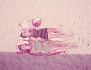 アメリカ合衆国 - 1940年代頃:水着を着た2人の女性、ビーチタオルの上に横たわり、日光浴。