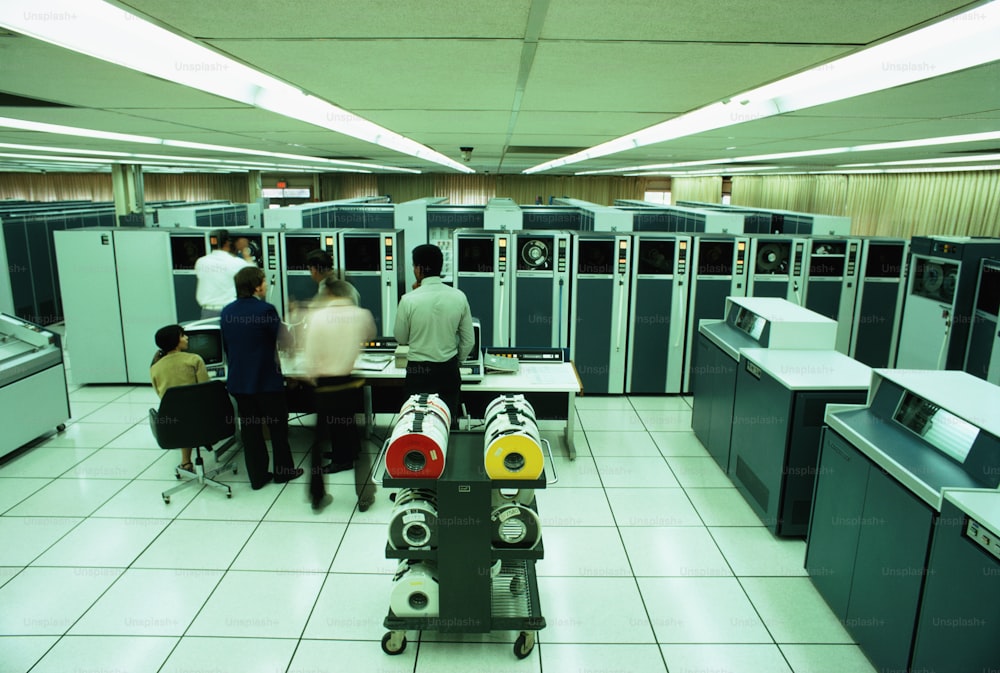 UNITED STATES - CIRCA 1970s:  Man mounting magnetic tape on tape transport, supervisory console in front, high speed line printers on side.
