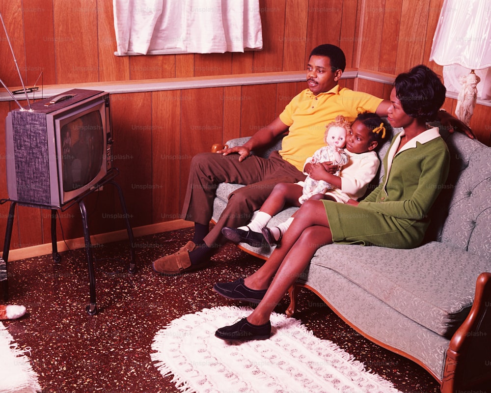 STATI UNITI - 1970 CIRCA: genitori e giovane figlia seduti in salotto, guardando la televisione.