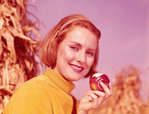 UNITED STATES - CIRCA 1960s:  Woman holding apple with bite out of it.