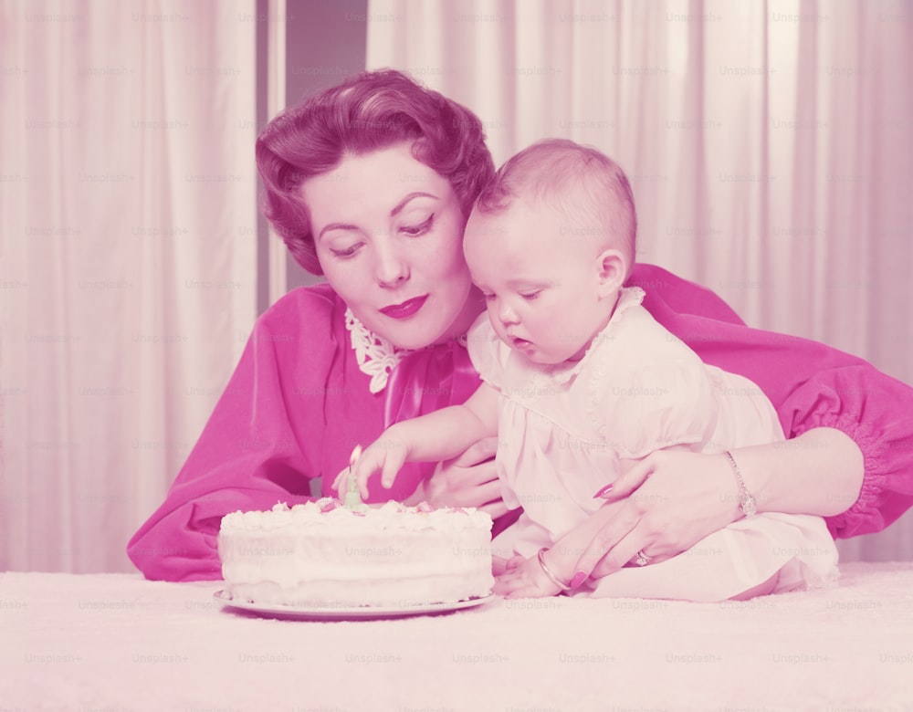 UNITED STATES - CIRCA 1950s:  Mother and one year old baby girl, with birthday cake.