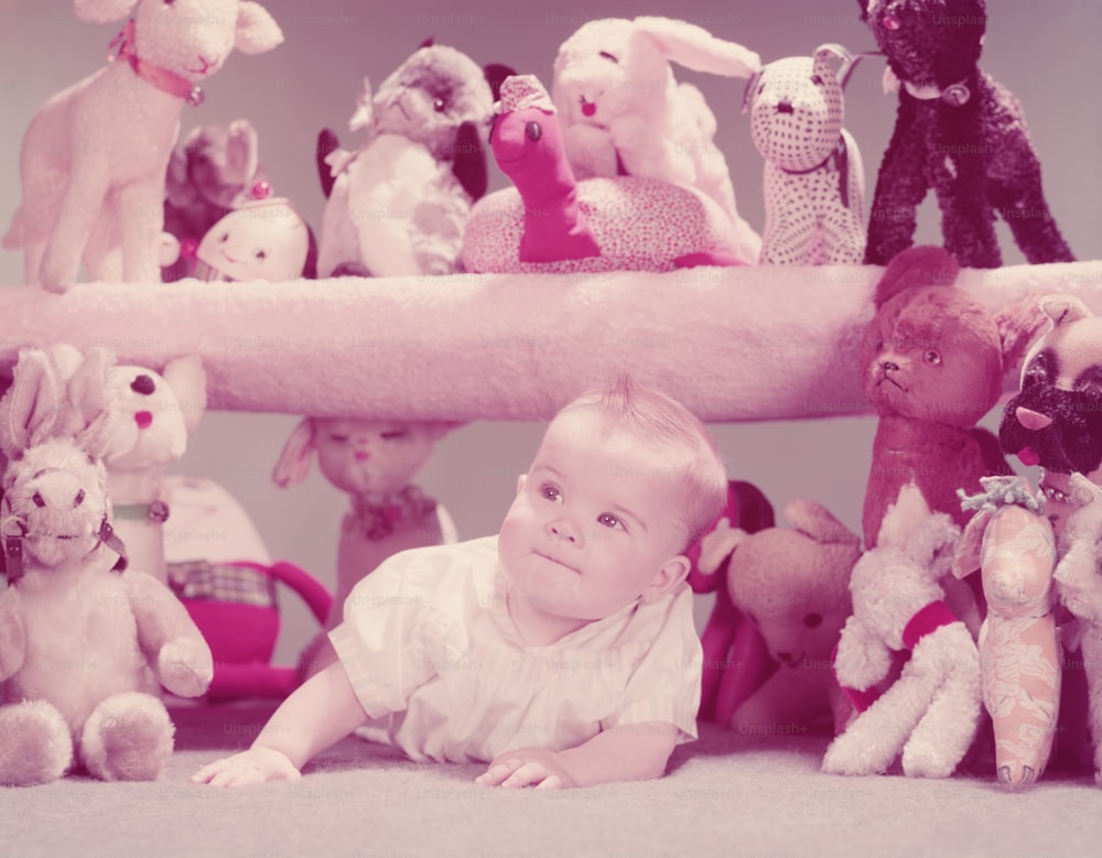 UNITED STATES - CIRCA 1950s:  Baby crawling under shelf filled with stuffed toy animals.