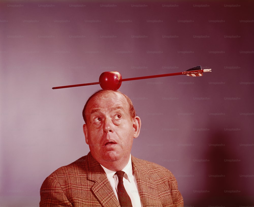 UNITED STATES - CIRCA 1970s:  Anxious looking man with apple pierced by arrow balanced on his head.