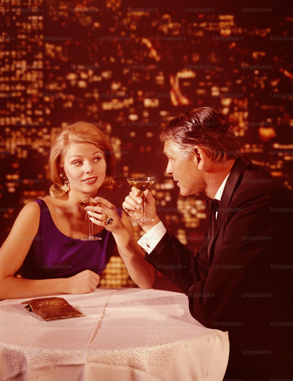UNITED STATES - CIRCA 1960s:  Romantic couple drinking champagne, city skyline at night in background.