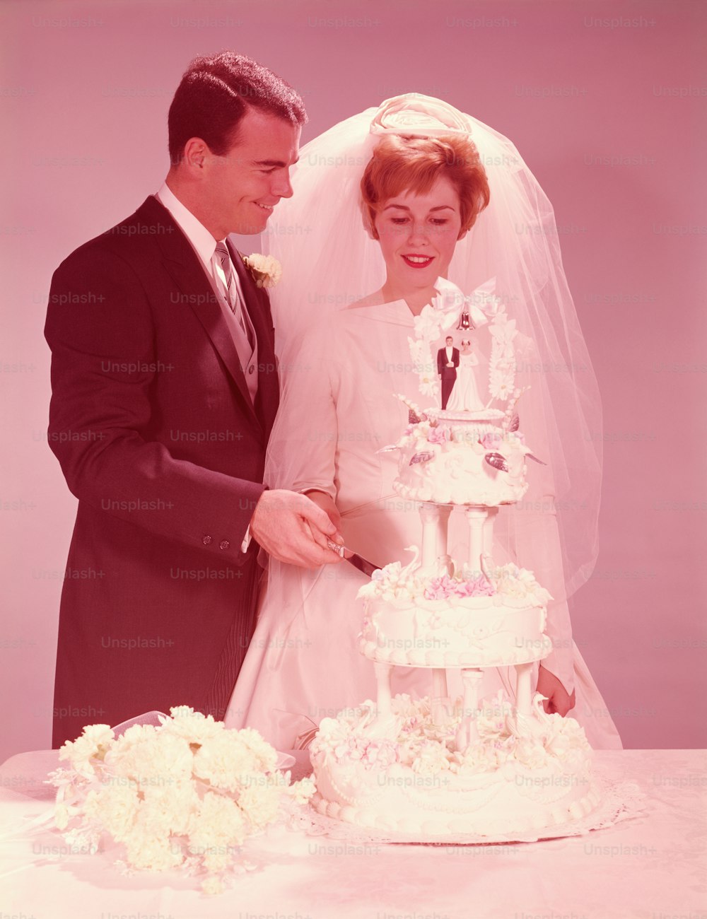 UNITED STATES - CIRCA 1950s:  Bride and groom cutting the wedding cake.