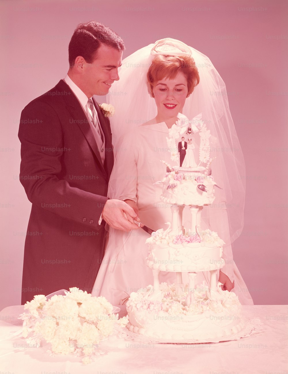 VEREINIGTE STAATEN - CIRCA 1950er Jahre: Braut und Bräutigam schneiden die Hochzeitstorte.