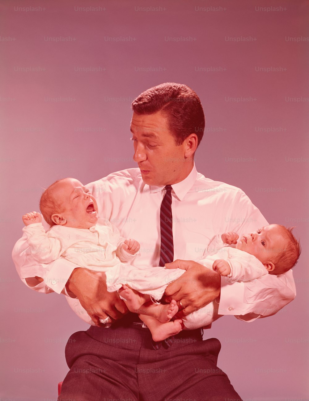 UNITED STATES - CIRCA 1960s:  Father holding crying twin babies.
