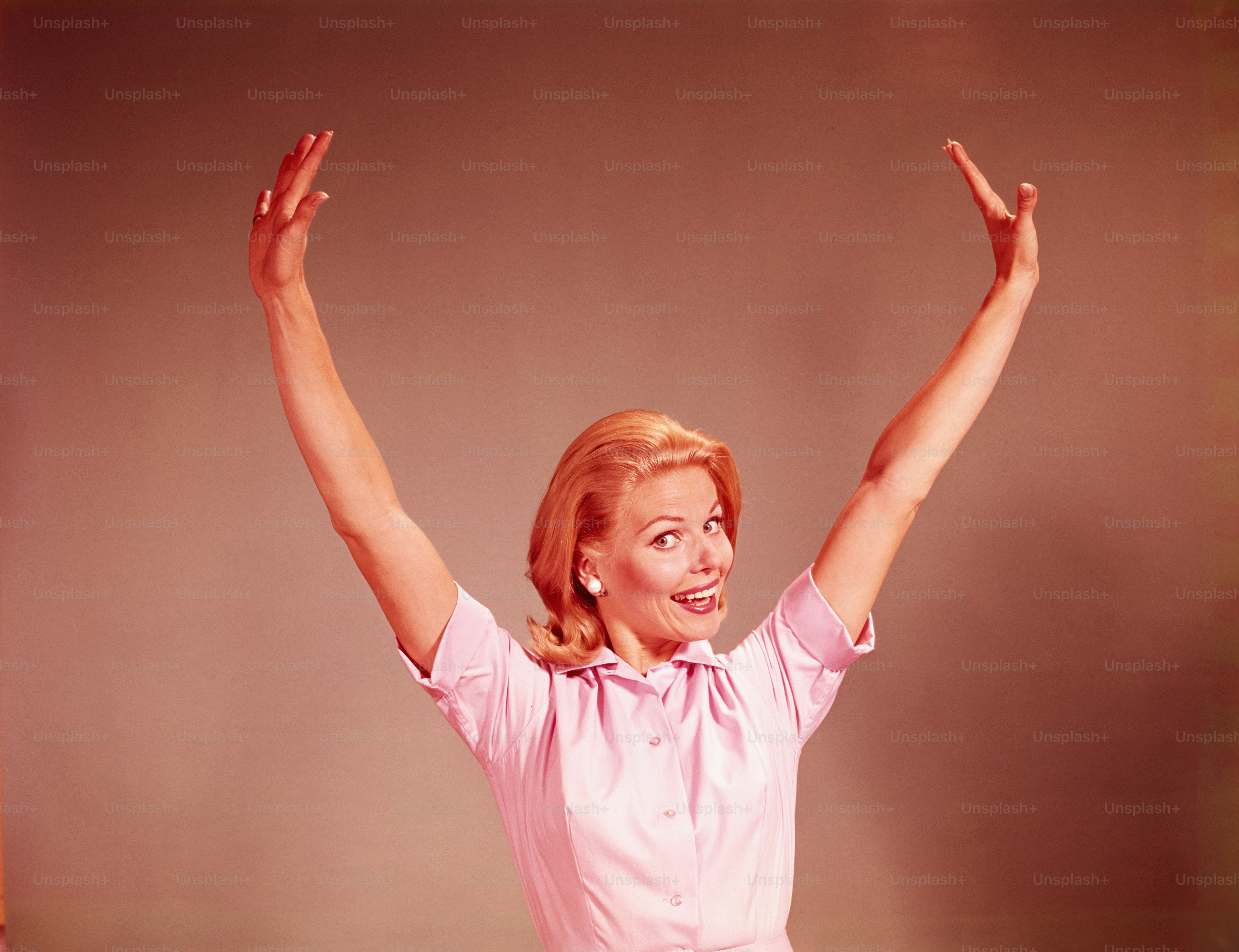 UNITED STATES - CIRCA 1960s:  Young woman smiling, stretching arms out and above head