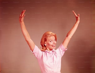 UNITED STATES - CIRCA 1960s:  Young woman smiling, stretching arms out and above head.