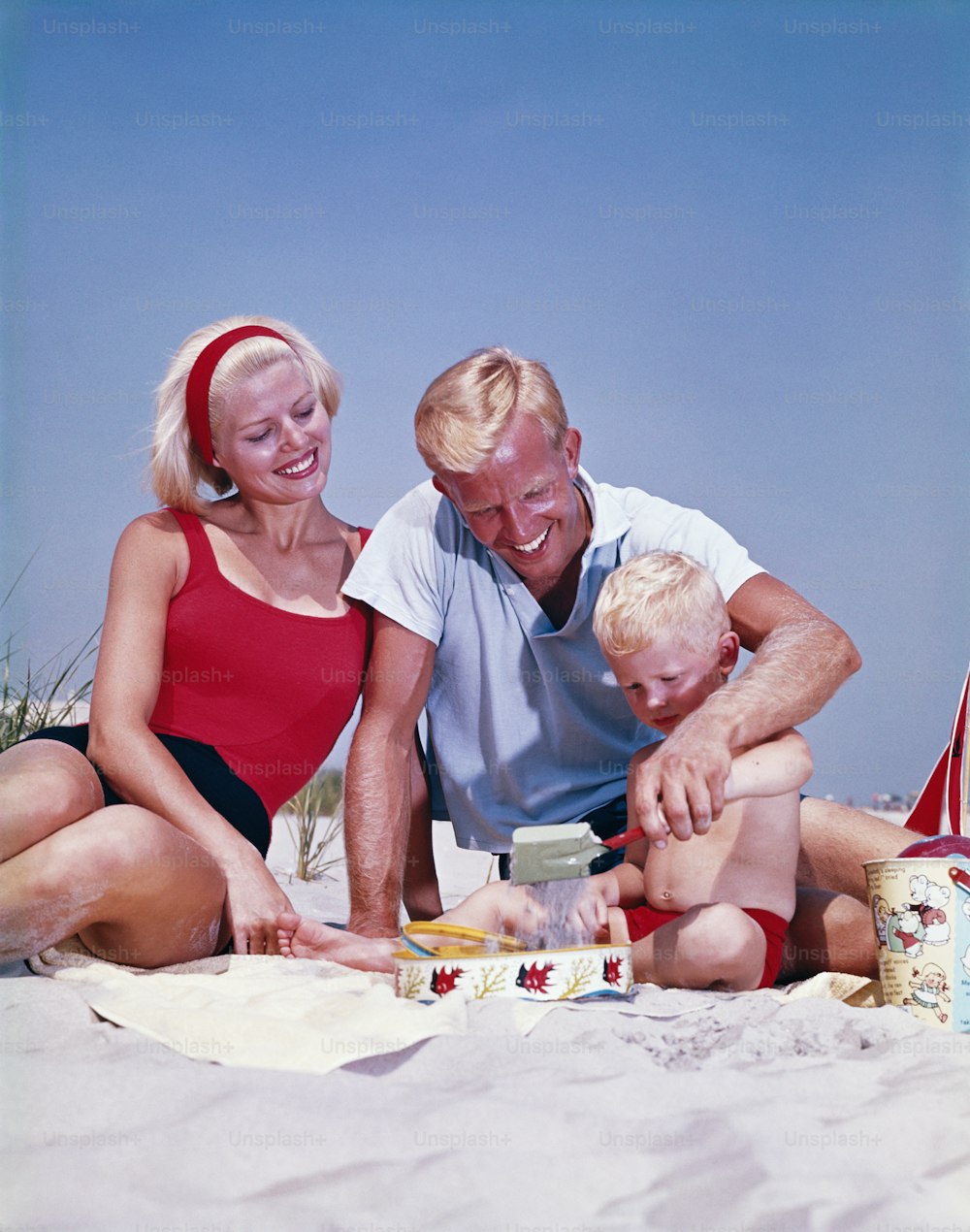 ESTADOS UNIDOS - CIRCA 1960s: Familia en la playa, niño jugando en la arena.