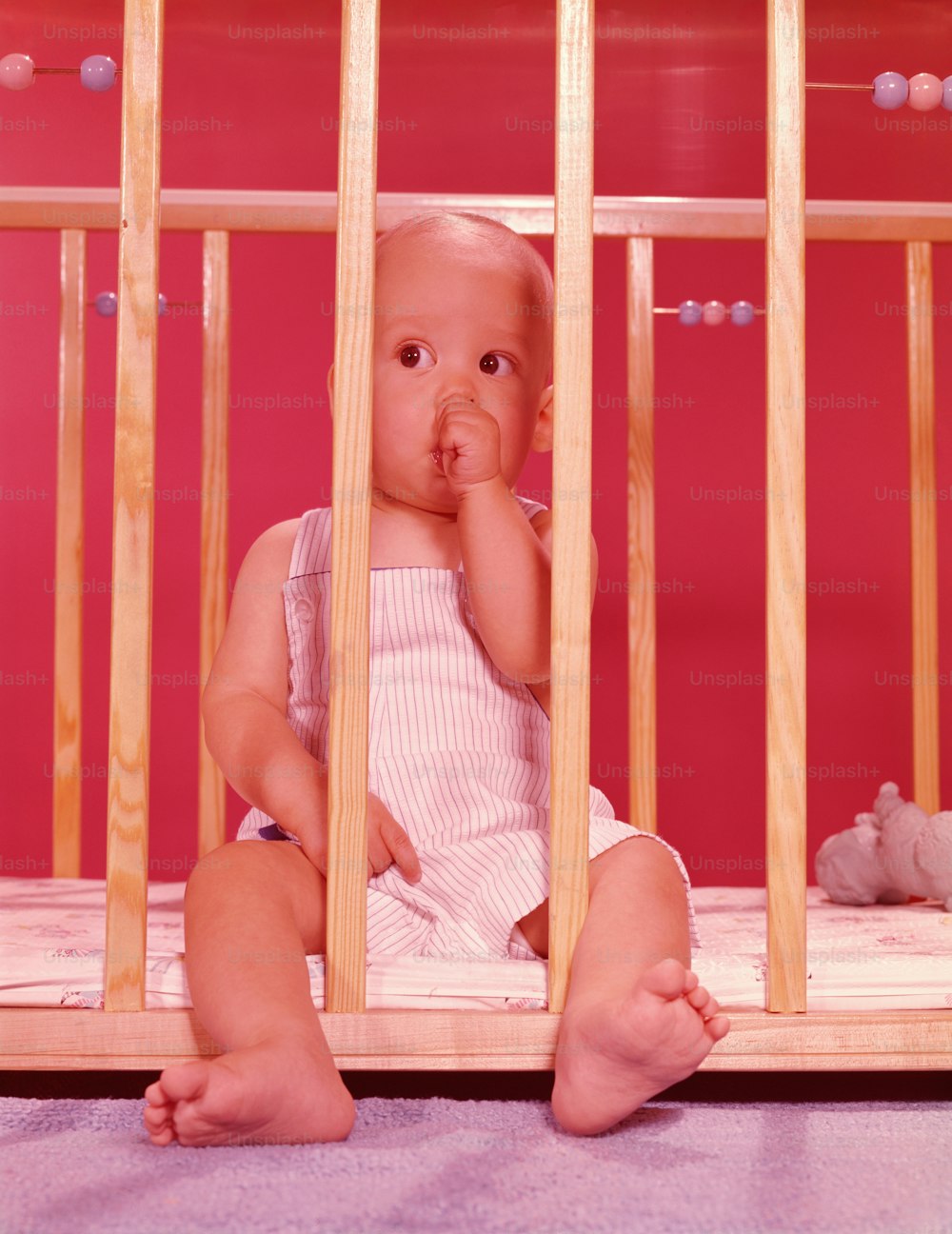 UNITED STATES - CIRCA 1950s:  Baby in playpen, sucking thumb.