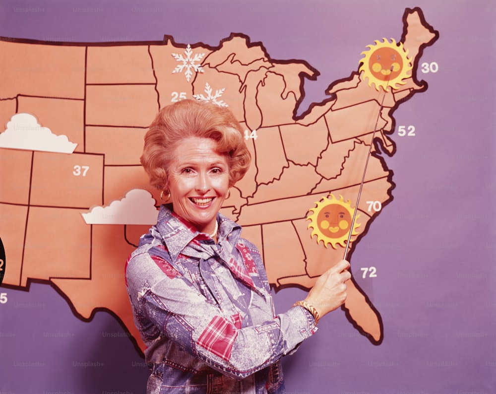 ESTADOS UNIDOS - CIRCA 1970s: Meteoróloga de pie frente a un mapa de Estados Unidos.