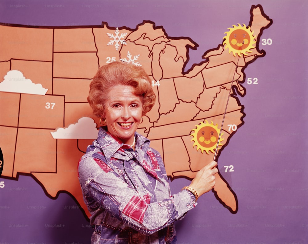 UNITED STATES - CIRCA 1970s:  Female meteorologist standing in front of map of United States.