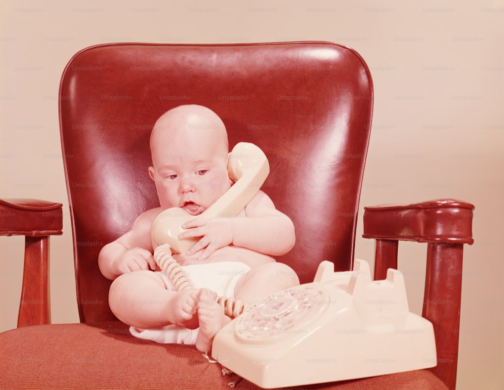 VEREINIGTE STAATEN - CIRCA 1950er Jahre: Baby saß am Schreibtisch und hielt Telefon.
