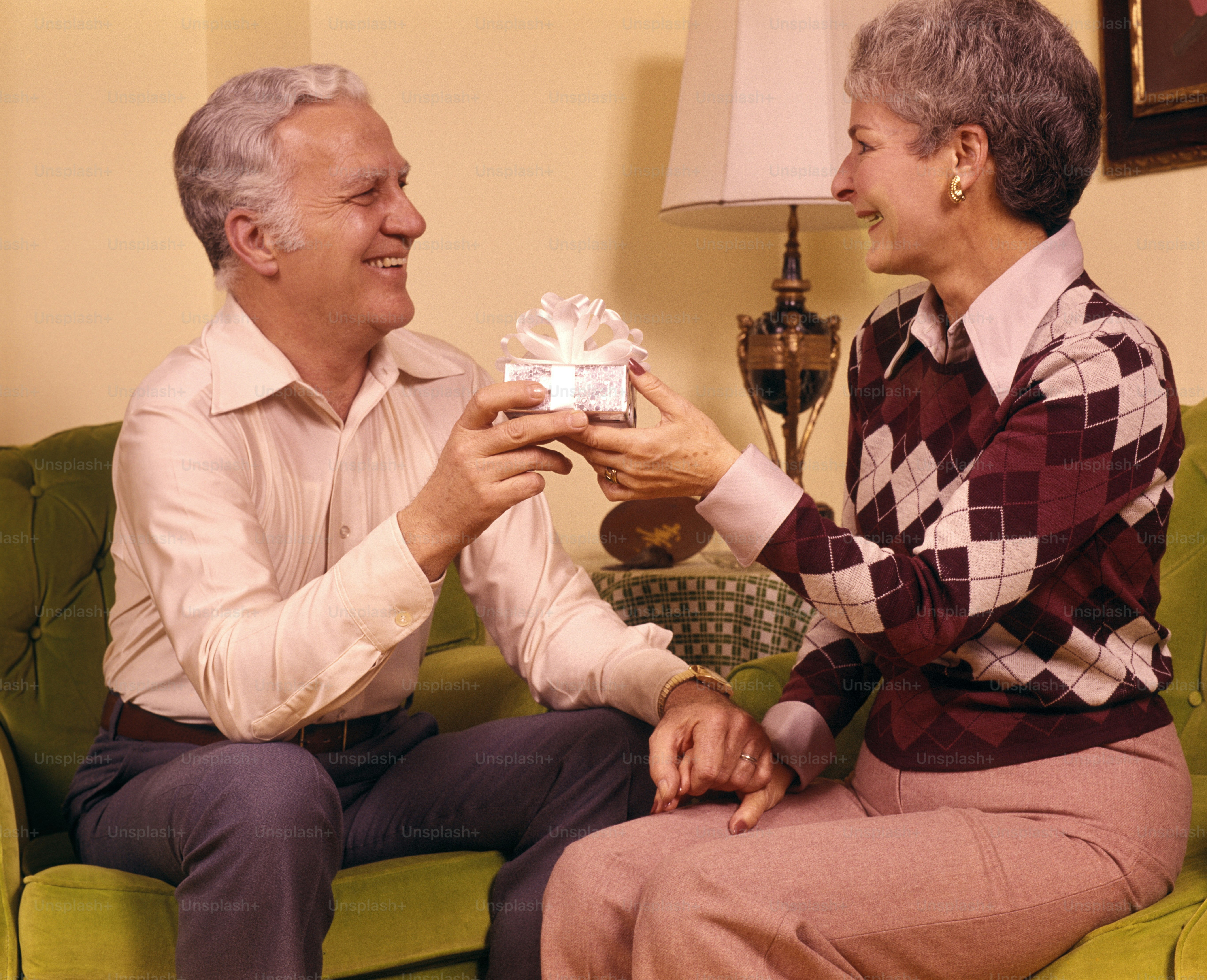 UNITED STATES - CIRCA 1970s:  Senior couple giving gift.