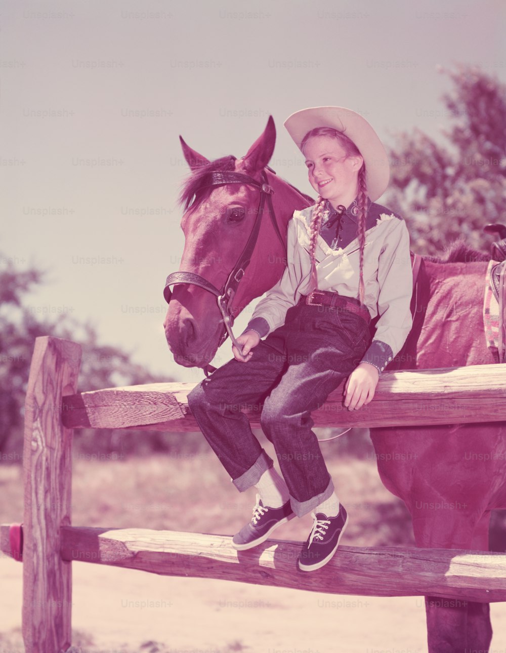 ESTADOS UNIDOS - POR VOLTA DE 1950: Menina usando chapéu de cowboy e rabos de porco com cavalo.