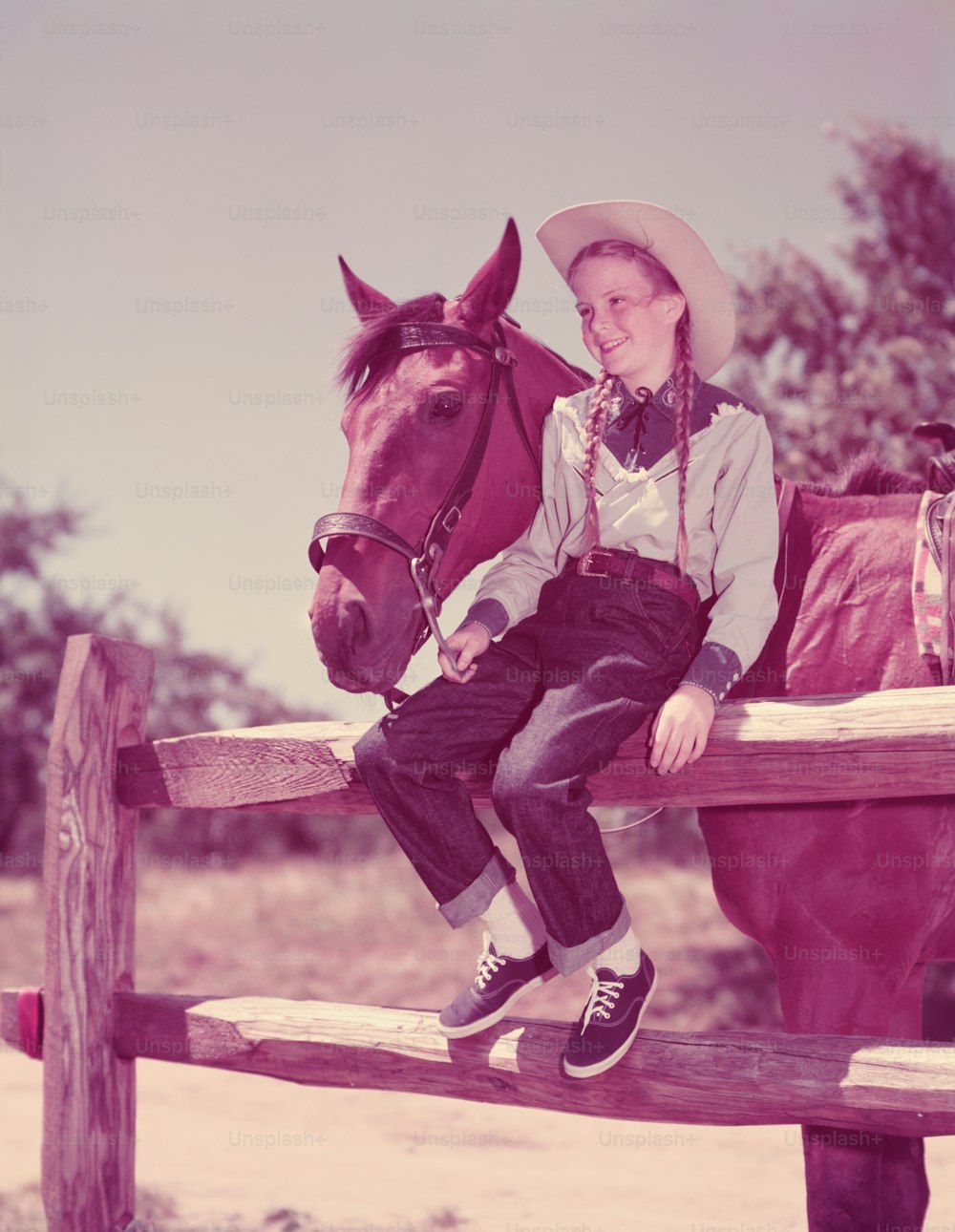 UNITED STATES - CIRCA 1950s:  Girl wearing cowboy hat and pigtails with horse.