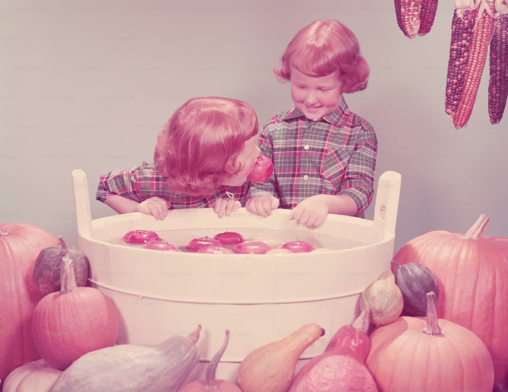 アメリカ合衆国 - 1950年代頃:パーティーでリンゴのために揺れる双子の赤毛の女の子。