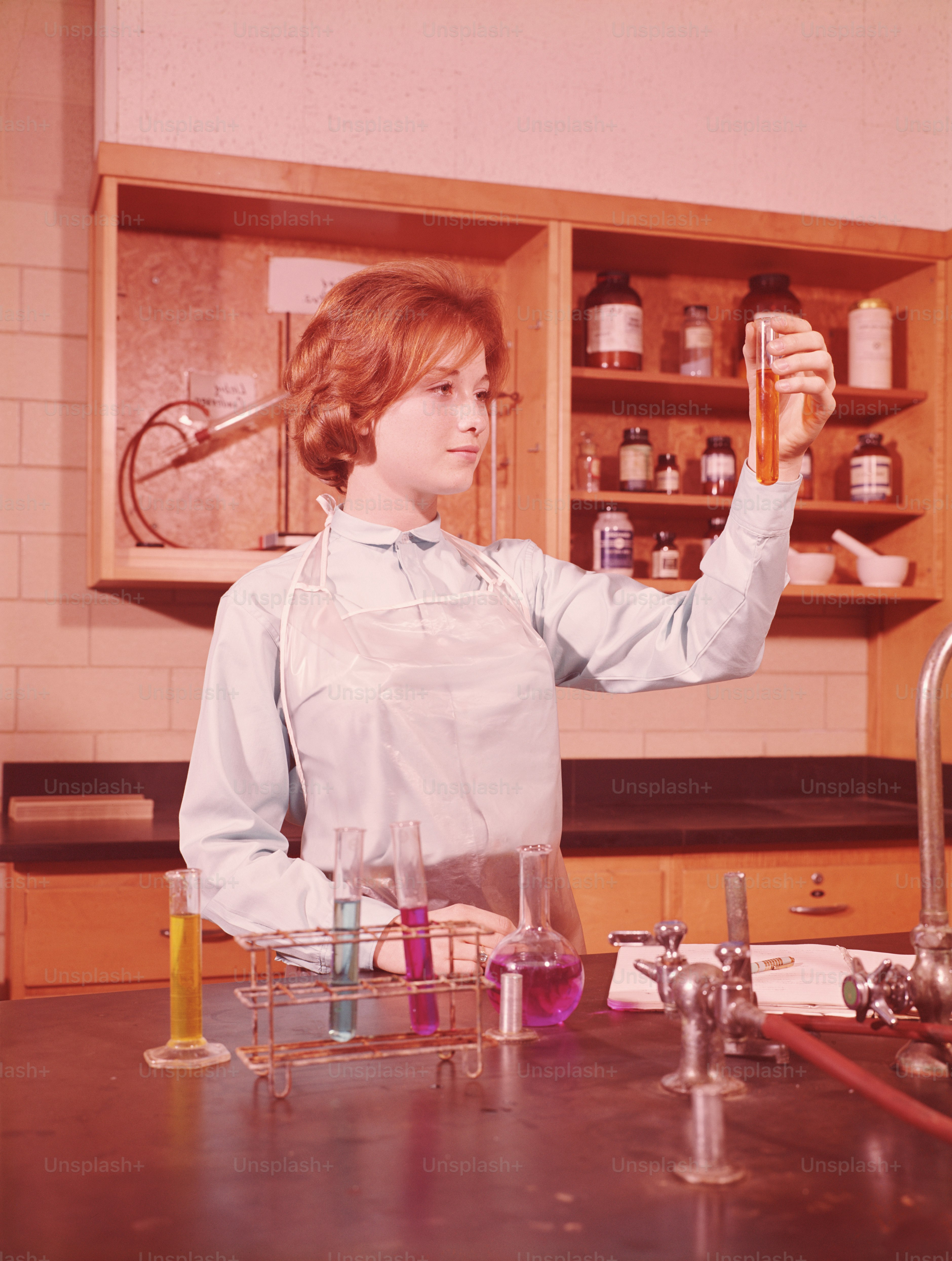 UNITED STATES - CIRCA 1960s:  Teenage female student holing up test tube in chemistry laboratory.