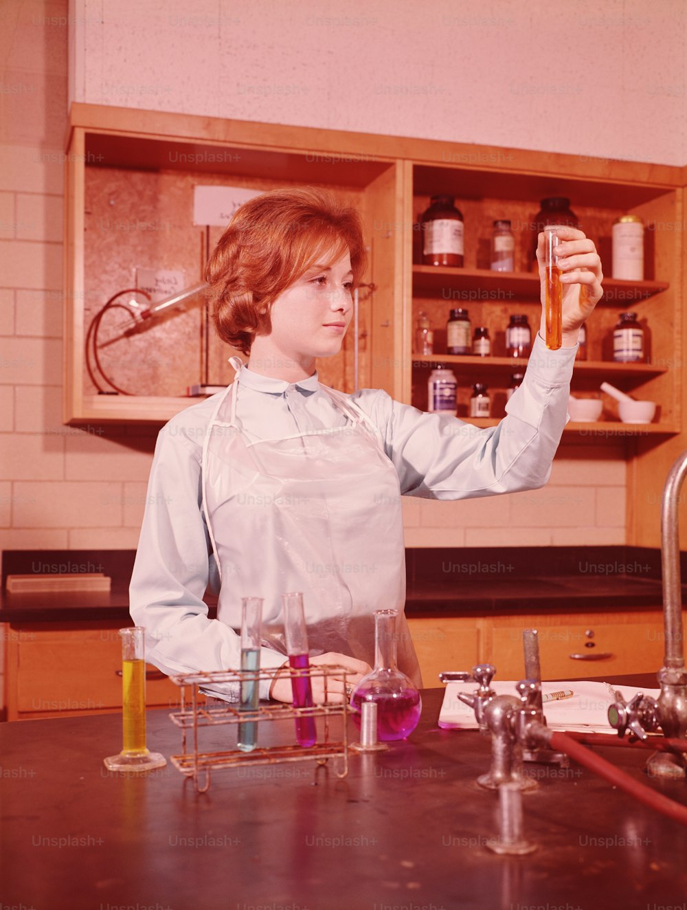 UNITED STATES - CIRCA 1960s:  Teenage female student holing up test tube in chemistry laboratory.