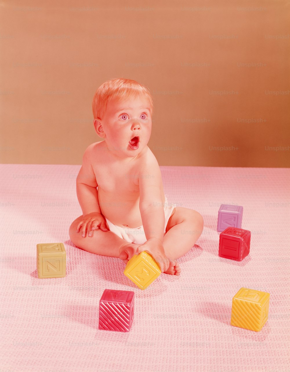 UNITED STATES - CIRCA 1950s:  Baby playing with multi-coloured plastic blocks.