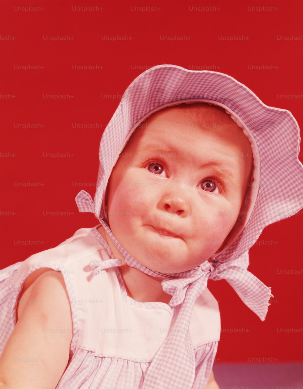 UNITED STATES - CIRCA 1950s:  Baby girl wearing bonnet and sundress, portrait.