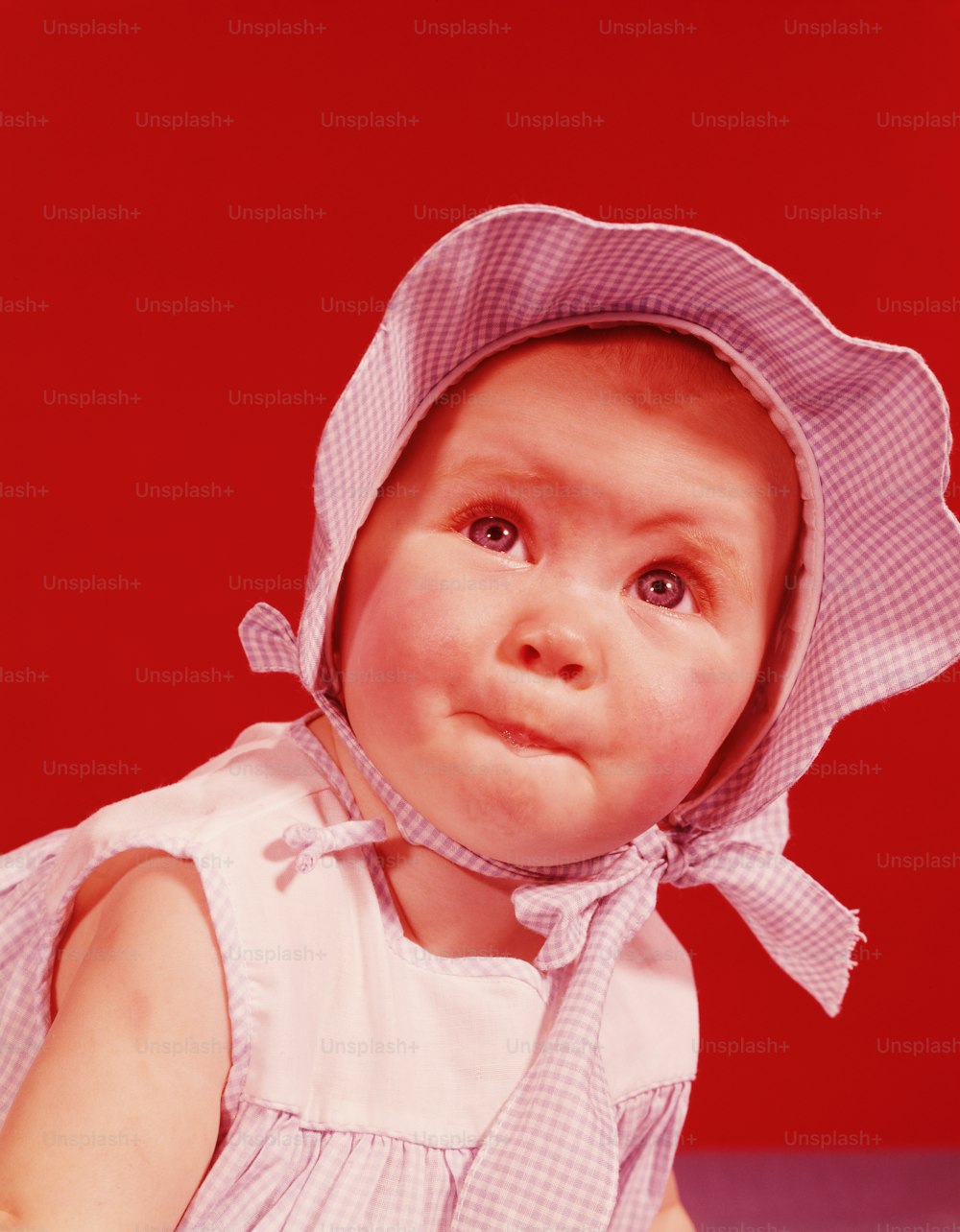 UNITED STATES - CIRCA 1950s:  Baby girl wearing bonnet and sundress, portrait.