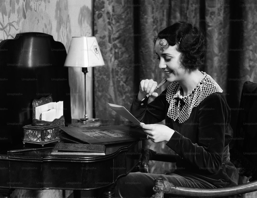 アメリカ合衆国 - 1930年代頃:自宅の机に座って手紙を書いている女性。