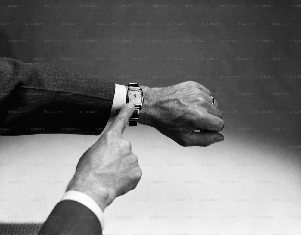 UNITED STATES - CIRCA 1950s:  Man's hand pointing at wristwatch.
