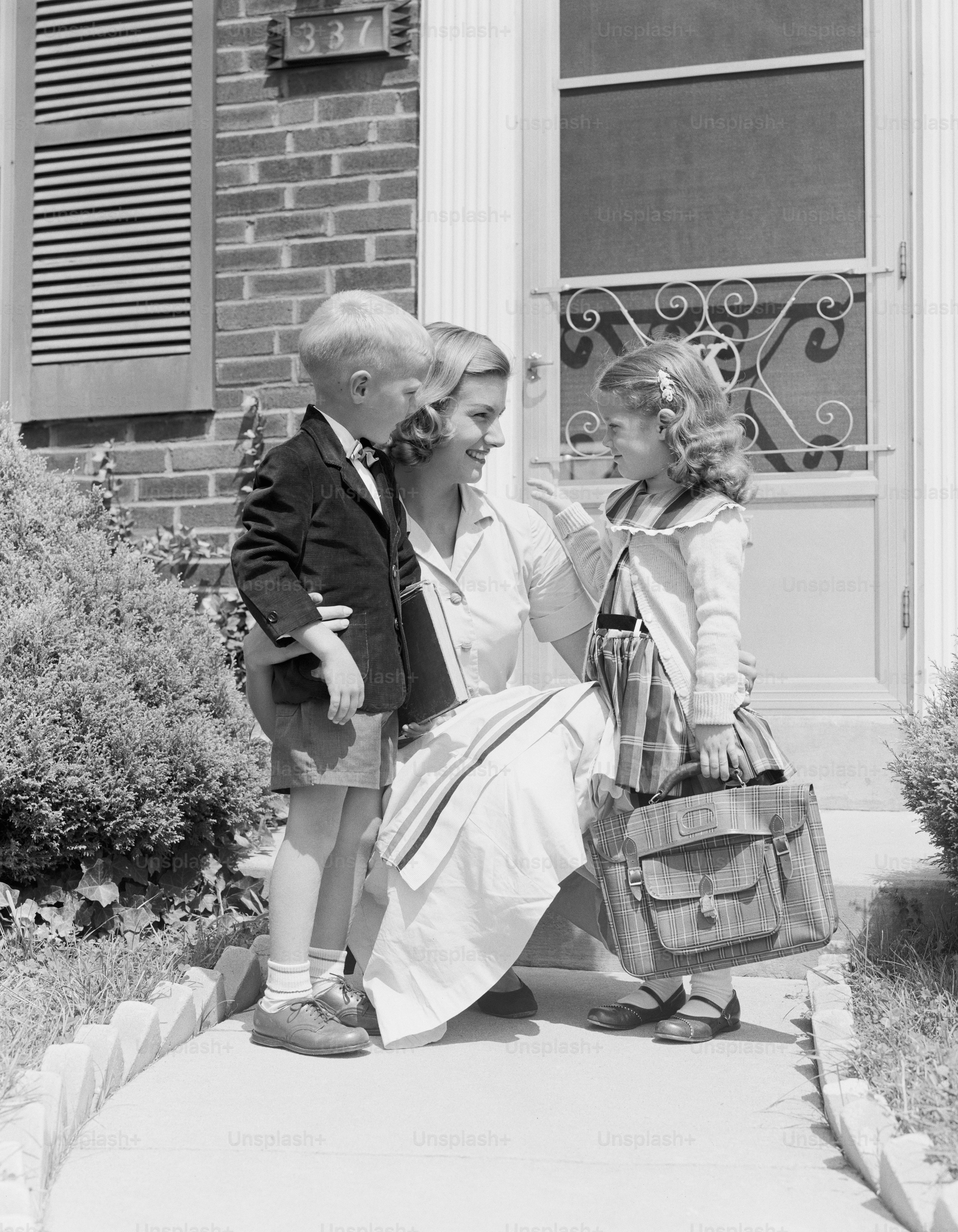Amerika Serikat - sekitar tahun 1950-an: Ibu berlutut dengan putra dan putri, di luar rumah.
