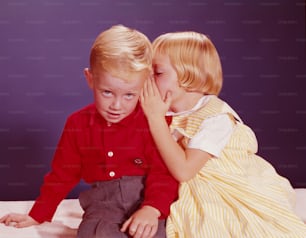 UNITED STATES - CIRCA 1950s:  Girl whispering in ear of boy.
